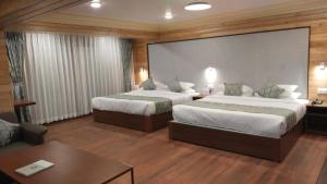 a hotel room with two beds and a table at Udaan Dekeling Resort, Darjeeling in Darjeeling