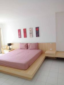a bedroom with a bed with pink sheets and paintings on the wall at Urban Patong Residence in Patong Beach