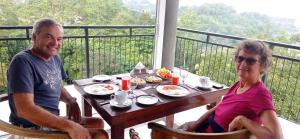 Ein älterer Mann und eine Frau sitzen an einem Tisch mit Essen in der Unterkunft Villa Forest View - No: 50/17 in Kandy