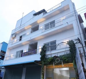 un bâtiment blanc avec des plantes sur les balcons dans l'établissement Viruksham Residency, à Palni