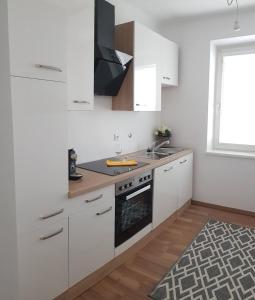 uma cozinha com armários brancos, um lavatório e um fogão em Top Appartement für Business-Wohnen-Urlaub em Wiener Neustadt
