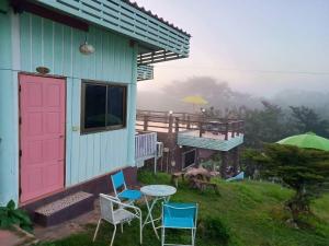 Ban Khao Ya Nua的住宿－หมอกอิงธาร รีสอร์ท เขาค้อ，粉红色的门、椅子和桌子的房子