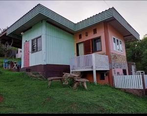 una casa con un banco delante de ella en หมอกอิงธาร รีสอร์ท เขาค้อ, en Ban Khao Ya Nua