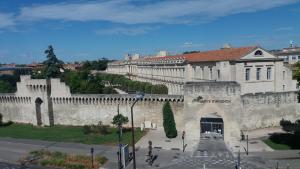 um grande edifício branco com uma parede e um pátio em ApartHotel Sainte-Marthe em Avignon