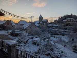 un pueblo cubierto de nieve con un coche aparcado en Studio des mésanges, en Saint-Laurent-la-Roche
