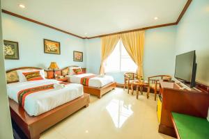 a bedroom with two beds and a flat screen tv at Soubundith Hotel in Pakse