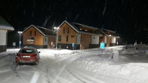 a car driving down a snow covered street at night at Lipno Apartments BERGMAX, Ski Areál Lipno 16min dojezd - Resort Malé Lipno s terasou a zahrádkou, parking free in Černá v Pošumaví