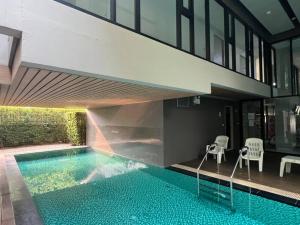 ein Haus mit einem Pool vor einem Gebäude in der Unterkunft Palm Spring Fountain 1 BDR @Nimman #Pool #Gym #Workcation in Chiang Mai