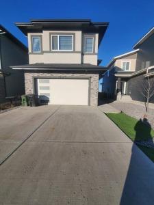a house with a white garage door in a driveway at Family-Friendly, NETFLIX, Cozy Comfy 2 bed room basement suite,sleeps 5 in Edmonton