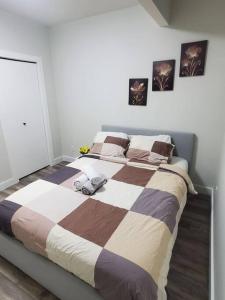 1 dormitorio con 1 cama grande y edredón a rayas en Family-Friendly, NETFLIX, Cozy Comfy 2 bed room basement suite,sleeps 5 en Edmonton