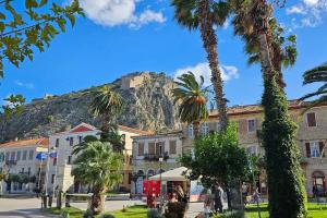 a mountain in the background of a town with palm trees at Kastro Residence in Nafplio