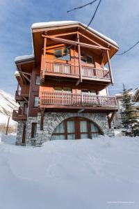 une maison en bois avec un balcon dans la neige dans l'établissement Ancolie 1er, à Val dʼIsère