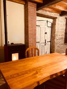 a dining room with a wooden table and a door at La So Casa -En el corazón de Asturias in Armiello