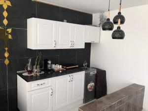 a kitchen with white cabinets and a black refrigerator at استراحة الدرر خاصه لنساء ولازواج 
