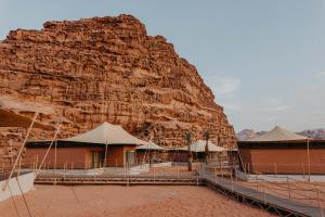 a building with umbrellas in front of a mountain at Valley Resort in Wadi Rum