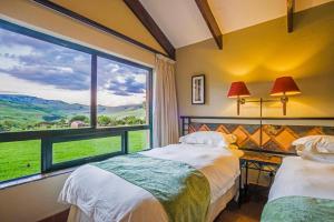 two beds in a room with a large window at aha Alpine Heath Resort in Bergville