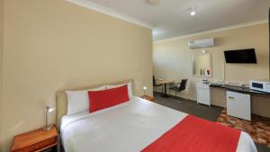 a hotel room with a large bed with a red pillow at Ashton Motel in Tumut