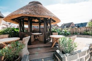 una terrazza in legno con gazebo, tavoli e sedie di Hotel Luina Beach a Büsum