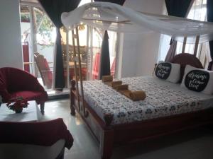 a bedroom with a bed with a canopy and a chair at Room in BB - Room Viv glaund flow with 2 guests in Nungwi