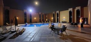 a swimming pool with a table and chairs in a building at Basrah International Airport Hotel in Al Başrah