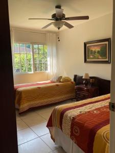 a bedroom with two beds and a ceiling fan at Hotel y villas palma Real . in La Ceiba