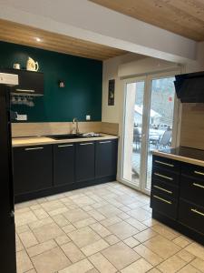 a kitchen with black cabinets and a large window at Domaine des oiseaux in Sapois