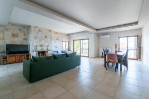 ein Wohnzimmer mit einem grünen Sofa und einem Tisch in der Unterkunft Apartment Villa Omega in Agia Pelagia