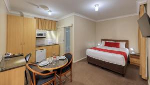 a hotel room with a bed and a table and a kitchen at Ashton Motel in Tumut