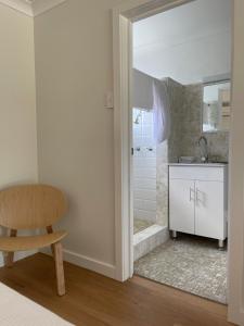 a bathroom with a shower and a chair and a sink at The Edgewater at Burrill in Ulladulla