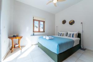 a bedroom with a bed with a blue blanket and a table at Apartment Villa Omega in Agia Pelagia