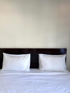 uma cama com almofadas brancas e uma cabeceira preta em Baan Kingkeaw Thamdee Patong em Patong Beach