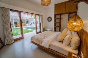 Schlafzimmer mit einem Bett und einem Kronleuchter in der Unterkunft Palm Merah Villas - Private pool in Selong Belanak