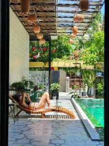 une femme en bikini sur une chaise à côté d'une piscine dans l'établissement Villa De Pi's Hoi An, à Hội An