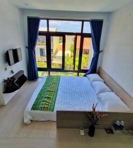 a large bed in a room with a large window at Villa De Pi's Hoi An in Hoi An