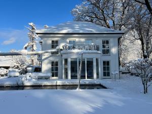 a white house with snow on the ground at Herrenhaus - Starnberger See - Ammerland in Münsing am Starnberger See