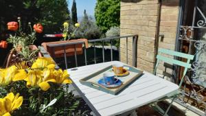 una mesa blanca con una taza y un platillo en un balcón con flores en La Casa Di Famiglia, en Asís