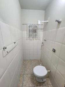 een witte badkamer met een toilet en een douche bij Quarto Guararema 2 in Guararema