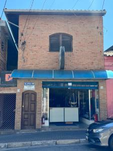een bakstenen gebouw met een blauwe luifel op een straat bij Quarto Guararema 2 in Guararema