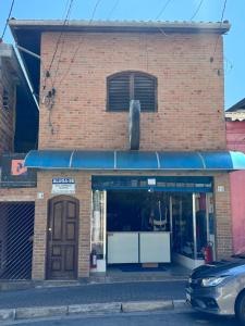 un bâtiment en briques avec un auvent bleu dans une rue dans l'établissement Quarto Guararema 2, à Guararema