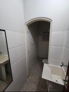La salle de bains blanche est pourvue d'un lavabo et de toilettes. dans l'établissement Quarto Guararema 2, à Guararema