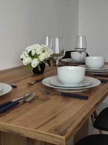 un tavolo in legno con piatti, bicchieri da vino e fiori di ***Santorini Apartament*** - 40m² ✓ a Rybnik