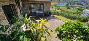 a patio with a bench and plants in front of a house at Your Happy Holiday Place in La Mercy