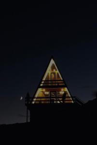 une maison au toit triangulaire avec la lune en arrière-plan dans l'établissement Arsha View, à Kazbegi