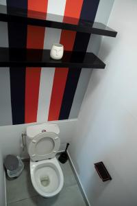 a bathroom with a toilet with a red white and black wall at L'élégance citadine in Cayenne