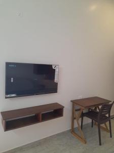 a tv on a wall with a table and a chair at Tamora By avea in Madurai