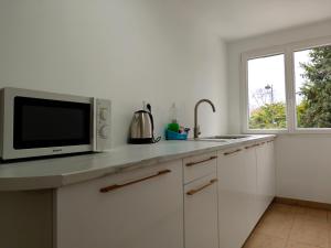 a white kitchen with a microwave and a sink at KoalaWakeup in Vitry-sur-Seine