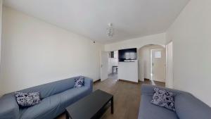 ein Wohnzimmer mit 2 blauen Sofas und einer Küche in der Unterkunft Superbe appartement à La Garenne Colombes in La Garenne-Colombes