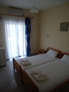 a bedroom with two twin beds and a window at Panorama Hotel in Ammoudia