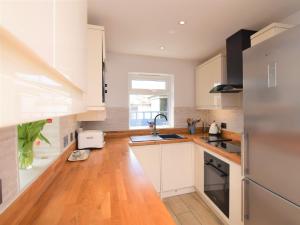 a kitchen with white cabinets and a wooden floor at 3 Bed in Brixham 75230 in Brixham