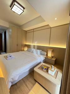 Un dormitorio con una gran cama blanca y una mesa en Wawa Guesthouse Pollux Habibie Batam Tower A 18, en Batam Centre
